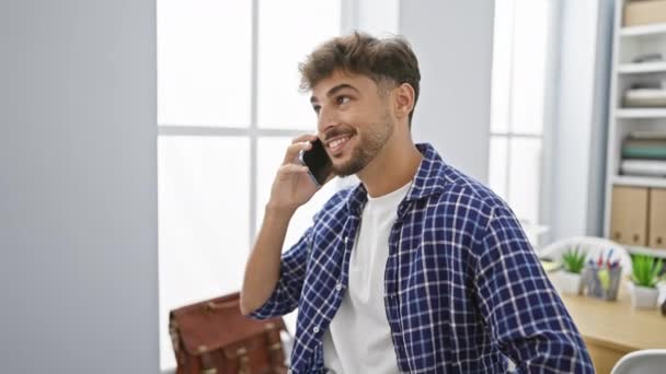 Itsevarma Nuori Arabialainen Liikemies Puhuu Iloisesti Älypuhelimellaan Työskennellessään Toimistossa Onnellinen — kuvapankkivideo