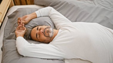 Genç, Latin asıllı, kır saçlı, yatakta yatan, yatak odasında uyuyan bir adam.