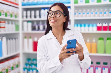 Genç ve güzel bir İspanyol eczacı eczanede çalışan akıllı telefonu kullanıyor.