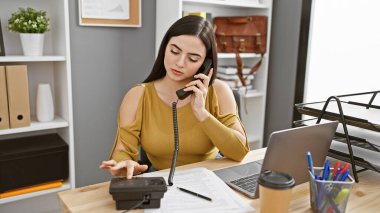 Profesyonel bir İspanyol kadın modern bir ofis ortamında telefon görüşmesi yapıyor.