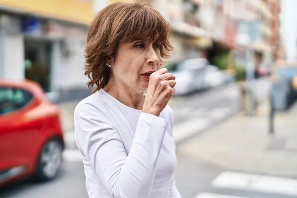 Middle age woman coughing at street