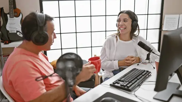 Man and woman interviewers sharing a coffee moment in a radio studio