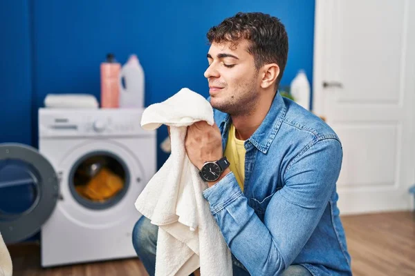Young Hispanic Man Smelling Towel Standing Laundry Room — Zdjęcie stockowe