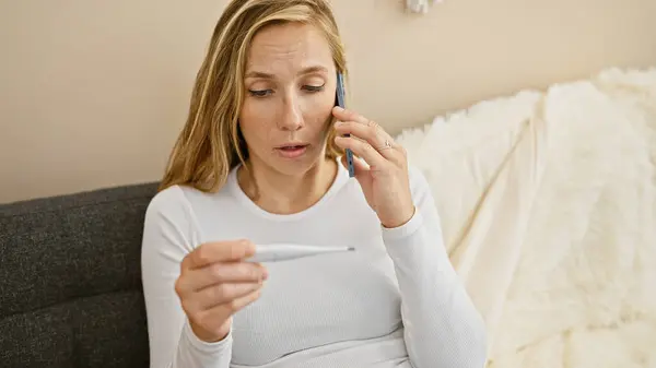 心配している若い白人女性が自宅で体温をチェックしながら電話で話し 潜在的な病気のシーンを作成します — ストック写真