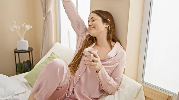 Relaxed Woman Pink Pajamas Sips Coffee Sunlit Bedroom Epitomizing Cozy — Stock Photo, Image
