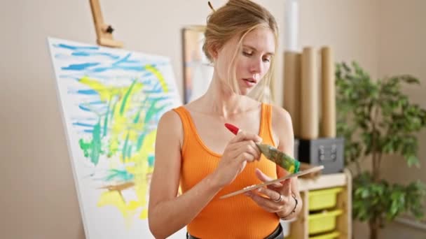 明るいスタジオのインテリアで絵を描くスマイルな白人女性アーティスト ブラシとパレットを保持 — ストック動画