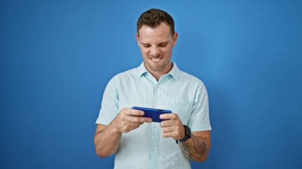 Homem Sorridente Com Tatuagens Usa Seu Smartphone Contra Fundo Azul — Vídeo de Stock