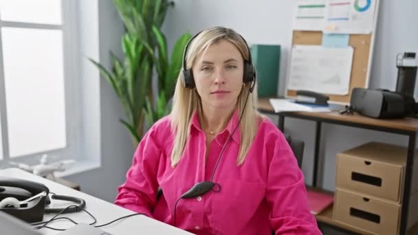 Μια Γυναίκα Αυτοπεποίθηση Που Φοράει Ακουστικά Κάθεται Στη Θέση Εργασίας — Αρχείο Βίντεο