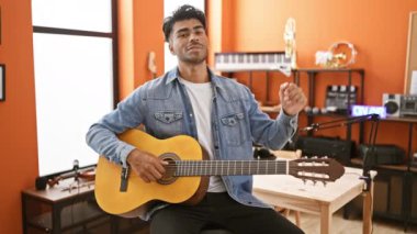 Bir müzik stüdyosunda gitar çalan yakışıklı İspanyol bir adam. Arka planda 