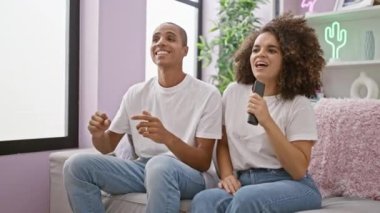 Güzel bir çift cumartesi gecesinin tadını çıkarıyor, şarkı söylüyor, dans ediyor, güzel evlerindeki kanepede gülüyor.