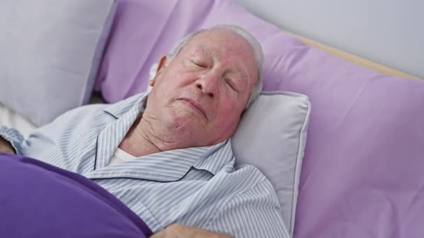 穿着时髦睡衣的快乐老人自信地坐在床上 清凉的笑容照亮了他成熟的脸 在舒适的卧室里体现了他积极的生活方式 — 图库视频影像