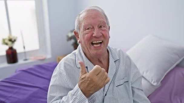Веселый Пожилой Человек Пижаме Сидит Кровати Удобной Комнате Указывая Сторону — стоковое видео