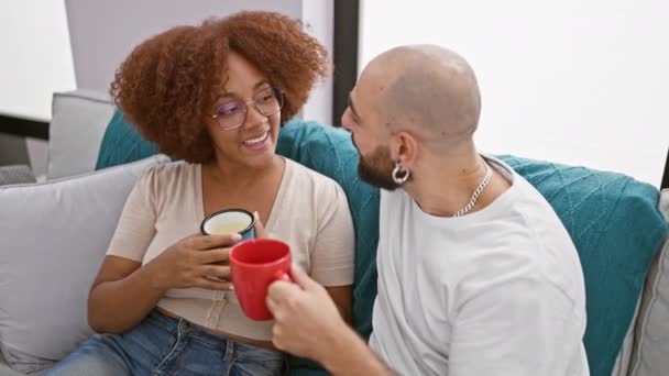 朝のコーヒーを楽しむ素敵な異人種間のカップルは 彼らのリビングルームの家庭的な雰囲気で自信を持ってチャット 幸せで輝く笑顔 — ストック動画