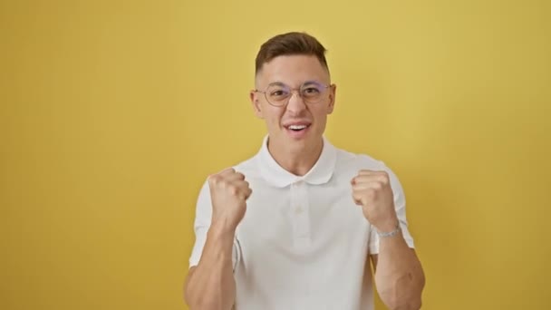 안경에 히스패닉 남자는 자신감과 행복을 노란색 배경에 즐거운 승리를 — 비디오