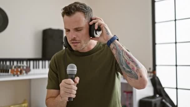 Przystojny Mężczyzna Brodą Śpiewający Mikrofonu Studiu Muzycznym Słuchawkami Klawiaturą — Wideo stockowe