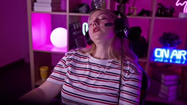 夜间在霓虹灯游戏室使用电脑的耳机中的焦点女性 — 图库视频影像