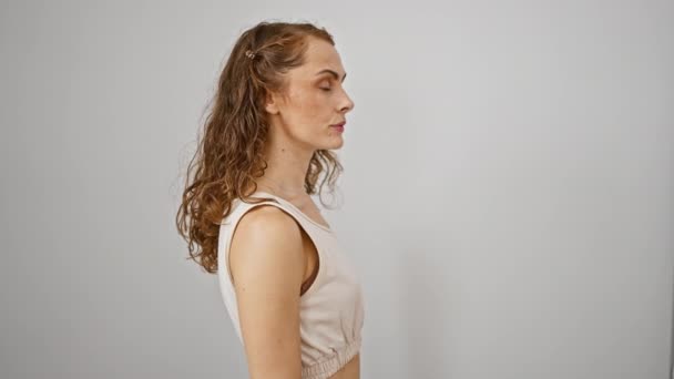 一个自信的年轻女人 自然地笑着 摆出一副轻松的姿势 站在旁边 望着白色孤立的背景 — 图库视频影像