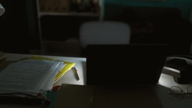 Ofiste geç saatlere kadar çalışan, belgelerin ve masa lambalarının arasında dizüstü bilgisayara odaklanmış genç bir İspanyol..