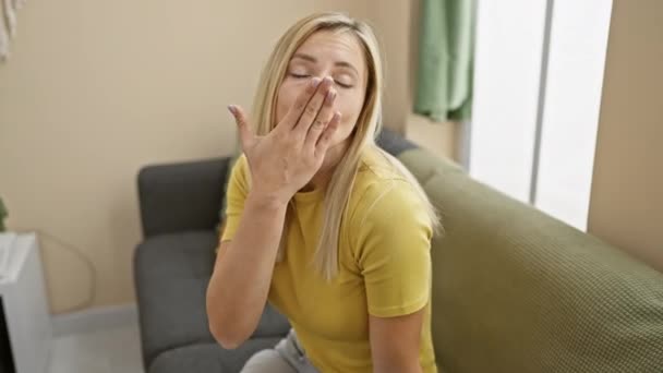 可爱的金发姑娘 穿着一件T恤衫 在镜头前打趣地吹着一个充满爱意的吻 从舒适的家散发着性感的自信 — 图库视频影像