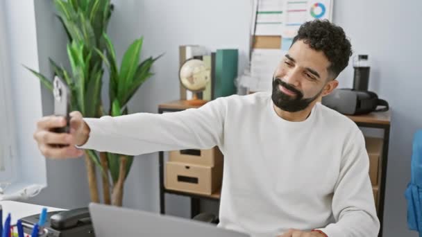 笑着带着胡子的男人拿着智能手机在他的现代办公空间里自私自利 — 图库视频影像