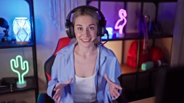 Kafkasyalı bir kadın, neon ışıklı bir oyun odasında kulaklık takıyor.