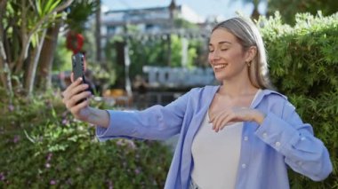 Genç kadın dışarıda selfie çekiyor, günlük kıyafetlerle doğanın tadını çıkarıyor, bir yaşam tarzını canlandırıyor..