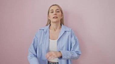 Depresyondaki genç sarışın kadın, kollarını kavuşturmuş, sıkılmış ve yorgun görünüyor, izole pembe bir arka plan, depresyonuyla boğuşuyor..