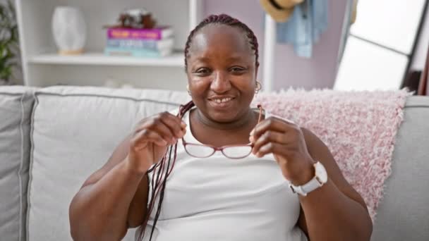 Χαρούμενη Αφροαμερικανή Γυναίκα Γυαλιά Που Χαλαρώνει Ευχάριστα Στον Άνετο Καναπέ — Αρχείο Βίντεο
