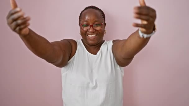 ジョイフルなアフリカ系アメリカ人女性は自信を持ってリラックスした表情で微笑み ピンクの背景に孤立したハート上の手 — ストック動画