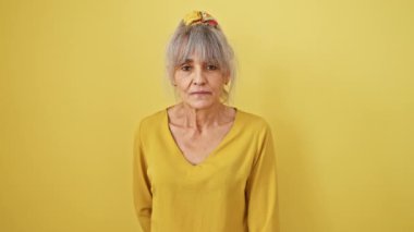 Sıcak kalpli, orta yaşlı, gri at kuyruklu bir kadın, yardım eli uzatılmış, güneşli sarı kesim arka planına karşı kabul gören kirişler..