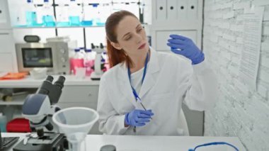Kafkasyalı bir kadın bilim adamı laboratuarda çalışıyor, mavi kimyasalları içeride analiz ediyor..