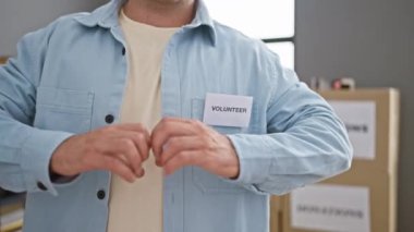 İç açıcı enstantane, genç, yakışıklı İspanyol gönüllü yardım merkezinde kalp hareketi yapıyor. Toplum desteği için öne çıkıyor.!