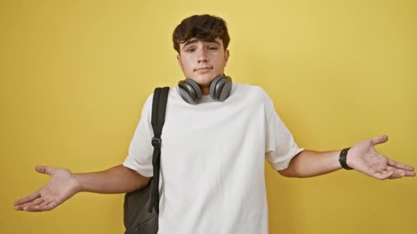 Bezradný Mladý Hispánský Teenager Sluchátkách Batohu Stojící Izolovaně Žlutém Pozadí — Stock video