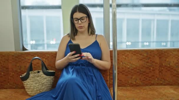 一个戴着眼镜的美丽的年轻惊慌失措的女人的迷人的肖像 在她拥抱城市生活的时候 她全神贯注地坐在电话里 一个人坐在空荡荡的地铁车厢里用智能手机 — 图库视频影像