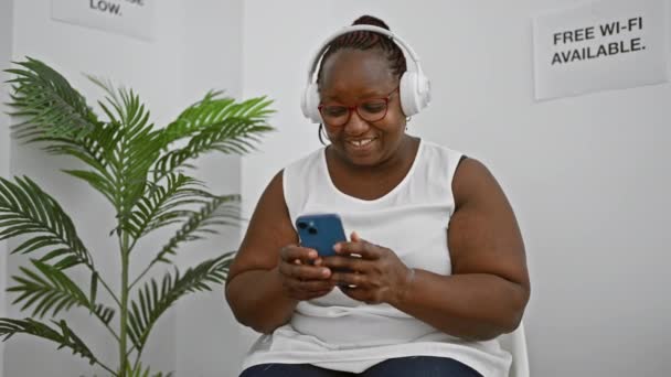 Усміхаючись Афроамериканка Дорослий Бос Носить Окуляри Насолоджуючись Піснею Своєму Смартфоні — стокове відео