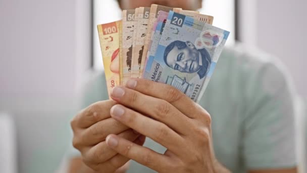 Allvarlig Ung Man Uppslukad Att Räkna Mexikanska Pesos Sedlar Soffan — Stockvideo