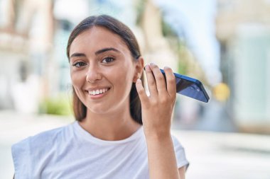 Genç ve güzel İspanyol kadın gülümsüyor. Caddedeki akıllı telefondan kendine güvenen bir sesli mesaj dinliyor.