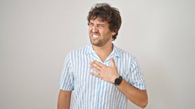 İzole edilmiş beyaz arka planda kalp ağrısı çeken genç İspanyol bir adam.