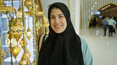 Müsrif bir cami lobisinde tesettür takan gülümseyen genç bir kadın..