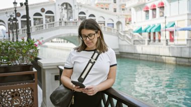 Qanat Quarter, Doha 'da akıllı telefon kullanan genç bir İspanyol kadın. Venedik tarzı mimarisi var.