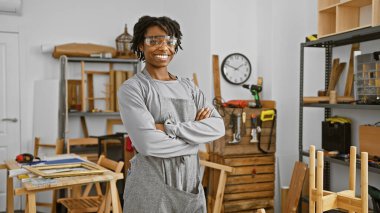 Marangozluk atölyesinde güvenlik gözlüğü takan kendine güvenen genç bir kadın..