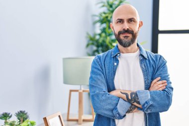 Young bald man smiling confident standing with arms crossed gesture at home