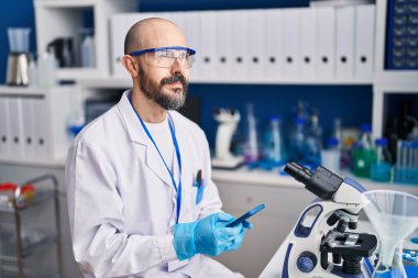 Genç kel bilim adamı laboratuvarda akıllı telefon kullanıyor.