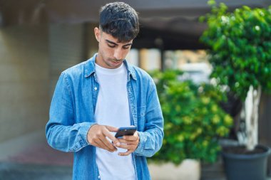 Genç İspanyol adam akıllı telefon kullanıyor. Sokakta ciddi bir ifadesi var.