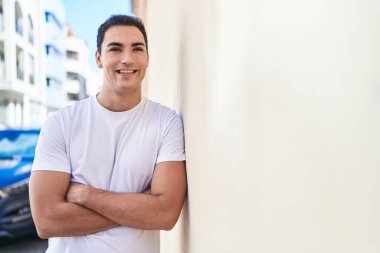 Sokakta kollarını kavuşturmuş İspanyol genç bir adam.