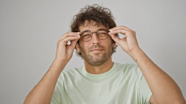 İzole edilmiş beyaz arka planda gözlük takan kendine güvenen İspanyol genç adam.