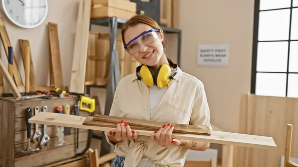 Uśmiechnięta Kobieta Okularami Ochronnymi Trzymająca Drewno Dobrze Wyposażonej Stolarni — Zdjęcie stockowe