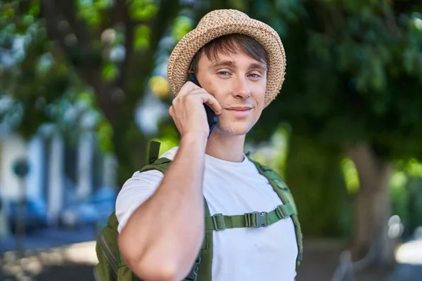 Young caucasian man tourist smiling confident talking on smartphone at park