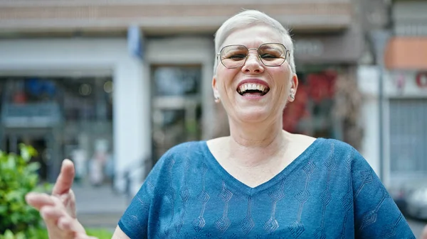 Middle age grey-haired woman laughing a lot at street