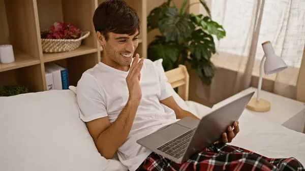 快乐的年轻人在网上愉快的视频通话中挥手致意 他们坐在床上 带着笔记本电脑 躺在舒适的卧室里 — 图库照片